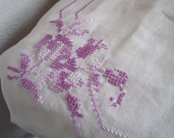 Linen table topper purple, lavender tone cross stitch 1970s w hand stitched edge in distressed condition. 44x44  inches. Ship incl.