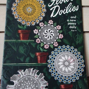 Könnte beinhalten: Ein Vintage-Buchumschlag mit einer Sammlung gehäkelter Blumen-Doilies. Der Umschlag ist grün mit einem weißen Rand und trägt den Text "Flower Doilies" in einer großen, dekorativen Schrift. Das Buch trägt den Titel "Star Book No. 64" und kostet 10 Cent.