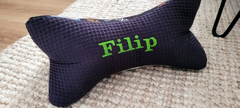 May include: A black and green bone-shaped pillow with the name "Filip" embroidered on it.