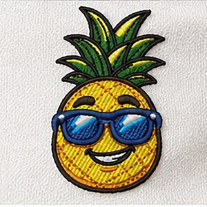 Peut inclure: Un écusson brodé thermocollant représentant un ananas jaune avec un motif quadrillé texturé. L'ananas a un sommet feuillu vert, une bouche souriante avec des dents blanches visibles et porte des lunettes de soleil bleu vif avec des reflets blancs.