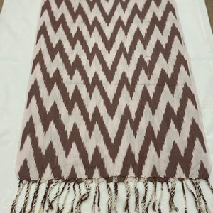 May include: A brown and white chevron patterned scarf with fringe tassels.
