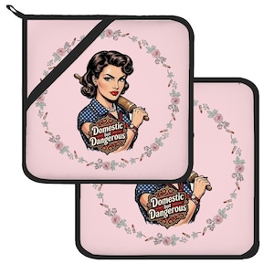 May include: Two square pink pot holders with black trim. Each features a retro-style illustration of a person holding a rolling pin, surrounded by a floral and lipstick wreath. The text "Domestic but Dangerous" is printed in a decorative frame.