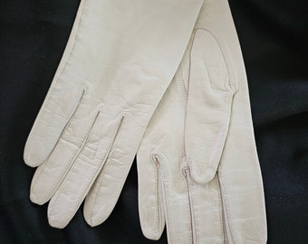 May include: A pair of off-white leather gloves. The gloves are made of a soft, supple leather and have a classic design.