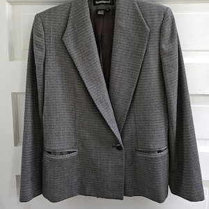 May include: A gray blazer with a black and white patterned design. The blazer has a single button closure and a long, pointed collar. The label "Harvey Bernard" is visible on the inside of the collar.