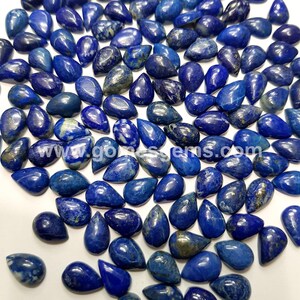 May include: A collection of blue pear-shaped lapis lazuli gemstones. The stones have a deep blue color with white and gold flecks.