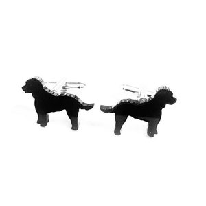 Pode incluir: Um par de botões de punho de silhueta de cão preto. Os botões de punho são feitos de metal e têm um acabamento brilhante.