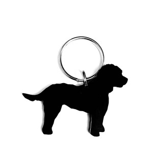 Puede incluir: Llavero de metal negro con la silueta de un perro. El llavero tiene un anillo plateado.