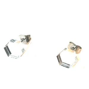 May include: A pair of silver hexagonal stud earrings. The earrings are simple and modern in design.