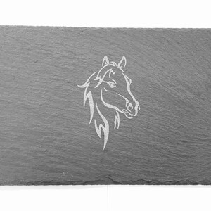 Pode incluir: Uma bandeja de servir de ardósia cinza com um desenho branco gravado de uma cabeça de cavalo.