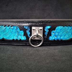 Peut inclure: Ceinture en cuir noir avec un motif de peau de serpent turquoise et un anneau en métal argenté.