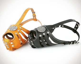 May include: Two leather dog muzzles, one brown and one black, with metal accents and a decorative design. Both muzzles have adjustable straps.