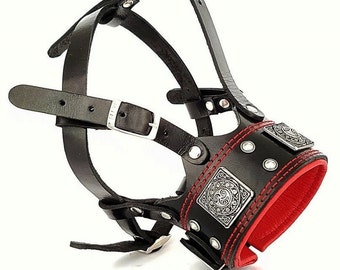 May include: Black leather dog muzzle with red stitching and silver accents. The muzzle has a decorative design on the front.
