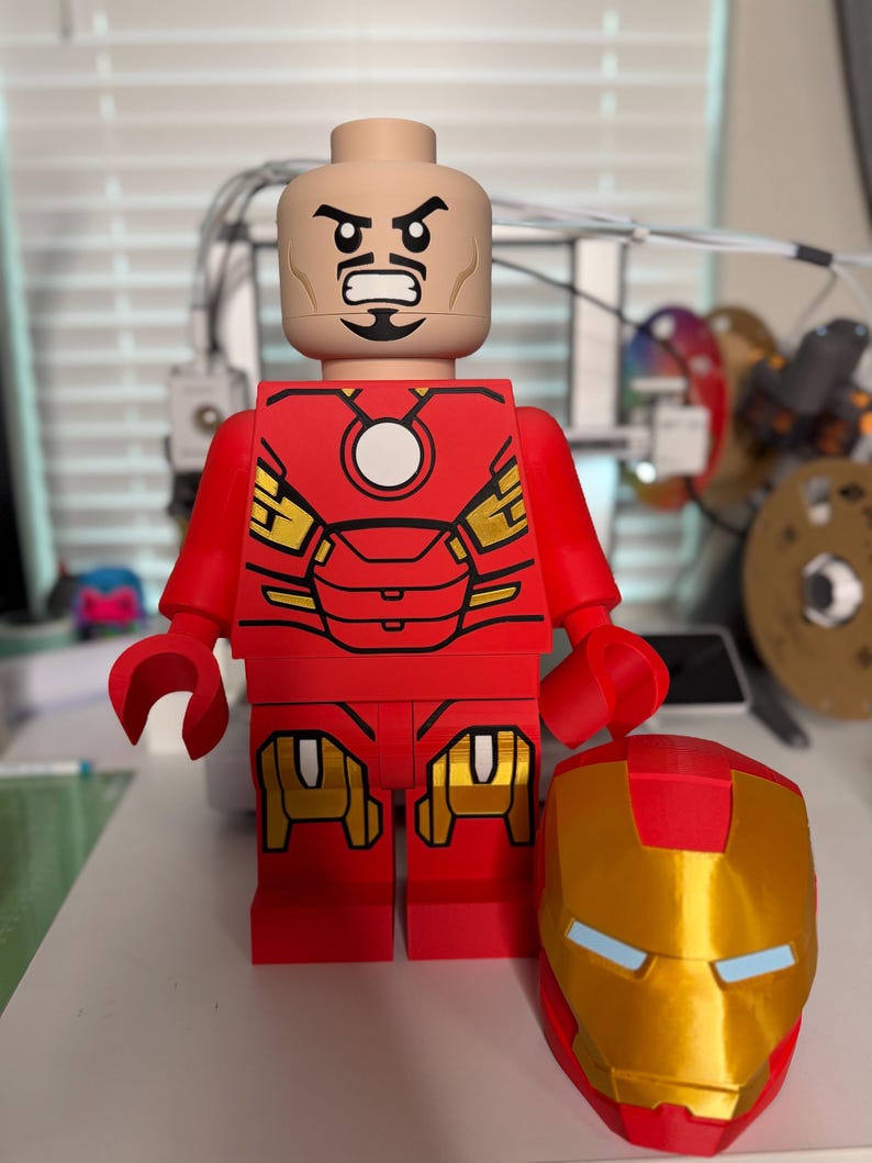 May include: A large red and gold Iron Man Lego figure with a removable helmet. The figure has a detailed red and gold suit design, a tan head with a stern expression, and is approximately 12 inches tall.