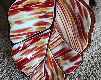 May include: A glass leaf-shaped serving dish with a red, white, and brown striped pattern. The dish is divided into sections.