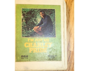 May include: A vintage off-white 8-track tape cartridge featuring a green label with a photograph of a man crouching outdoors. The text reads I'M JUST ME CHARLEY PRIDE, with RCA P8S-1772 and STEREO 8 VICTOR printed in black at the bottom of the label.