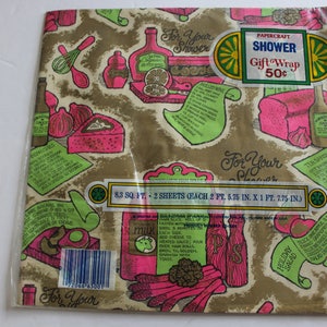 K&ouml;nnte beinhalten: Ein Vintage-Geschenkpapier f&uuml;r eine Dusche mit goldfarbenem Hintergrund und rosa und gr&uuml;nen Illustrationen von Speisen und K&uuml;chenutensilien. Der Text "For Your Shower" wird im gesamten Design wiederholt. Das Papier ist mit "Papercraft Shower Gift Wrap 50c" beschriftet.