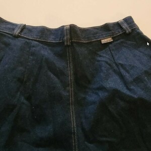 May include: A dark blue denim skirt with a center seam and a small label on the back waistband.