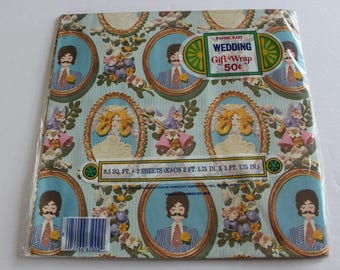 May include: Wedding gift wrap paper with a blue and white background. The paper features a repeating pattern of couples in wedding attire, flowers, and bells. The text "PAPERCRAFT WEDDING Gift Wrap 50c" is printed on the paper. The paper is 8.3 square feet and comes in two sheets, each measuring 2 feet 5.75 inches by 1 foot 7.75 inches.