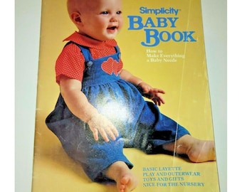 May include: A Simplicity Baby Book with a yellow cover featuring a baby wearing a red polka-dot shirt and blue overalls with heart appliques. The text reads Simplicity Baby Book, How to Make Everything a Baby Needs, Basic Layette, Play and Outerwear, Toys and Gifts, Nice for the Nursery.
