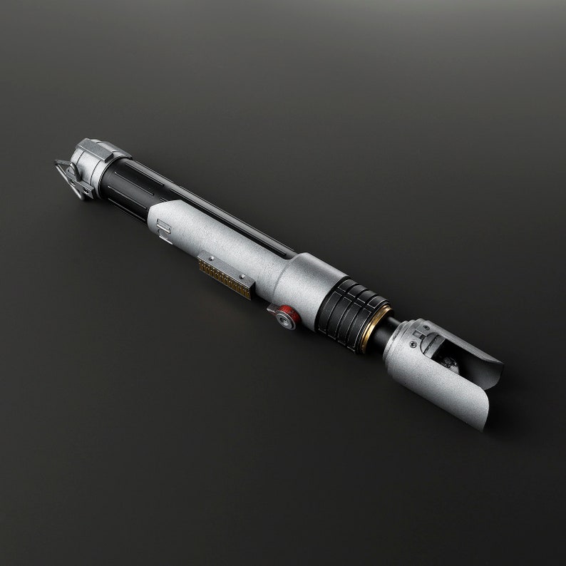 Peut inclure: Un sabre laser argent&eacute; et noir avec un accent dor&eacute; et un bouton rouge. Le sabre laser a une surface textur&eacute;e et une poign&eacute;e noire.