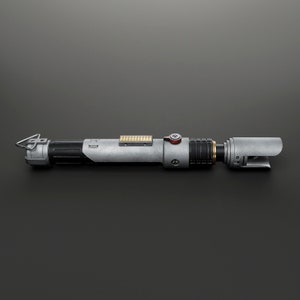 Peut inclure: Un sabre laser argent&eacute; et noir avec un bouton rouge et un d&eacute;tail dor&eacute;. Le sabre laser a une poign&eacute;e noire et une lame argent&eacute;e.