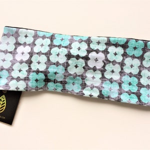 May include: A turquoise and grey headband with a floral pattern. The headband is made of soft, stretchy fabric and is ideal for keeping hair out of your face.