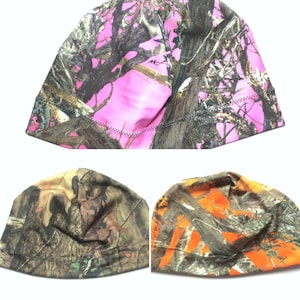 May include: Three camouflage patterned beanies in pink, brown, and orange. The beanies have a black stitched seam around the edge.