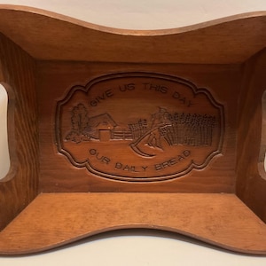 May include: A wooden bread basket with a carved design that says "Give us this day our daily bread".