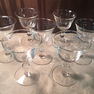 May include: Set of six clear glass stemmed cocktail glasses. The glasses have a wide bowl and a short stem.