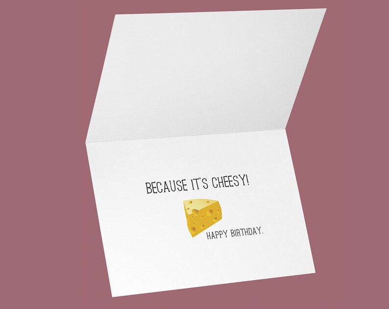 May include: A white greeting card with the text "BECAUSE IT'S CHEESY!" and "HAPPY BIRTHDAY." A yellow cheese wedge illustration is also featured on the card. The card is open, revealing the inside.