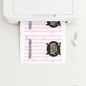 May include: A sheet of paper with a printed design is being printed from a white printer. The design includes pink stripes, stars, and a black cauldron with the text "a little BREW FOR ALL YOU DO". The text "THANK YOU FOR BEING A SPOOKTACULAR TEACHER" is also visible.
