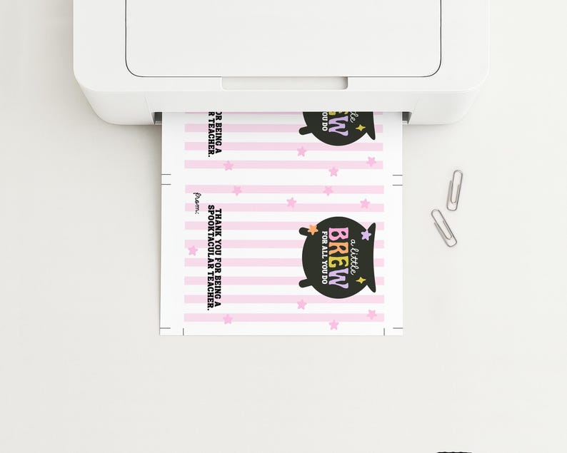 May include: A sheet of paper with a printed design is being printed from a white printer. The design includes pink stripes, stars, and a black cauldron with the text "a little BREW FOR ALL YOU DO". The text "THANK YOU FOR BEING A SPOOKTACULAR TEACHER" is also visible.