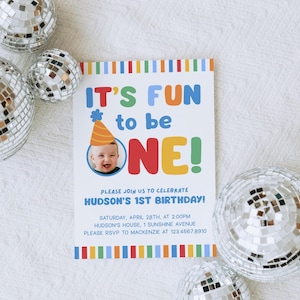 Pu&ograve; includere: Un invito di compleanno con la scritta "IT'S FUN to be ONE!" in lettere colorate. L'invito include una foto di un bambino con un cappello da festa. Decorato con strisce colorate e sfere a specchio.