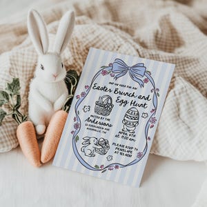 May include: A white plush bunny with long ears sits next to two orange carrots and an Easter Brunch and Egg Hunt invitation. The invitation has a blue striped background and features a bow, flowers, and Easter-themed illustrations.