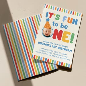May include: A birthday invitation with the text "IT'S FUN to be ONE!" in colorful letters. The invitation includes a photo of a baby wearing a party hat. The invitation has a striped pattern on the back and edges.