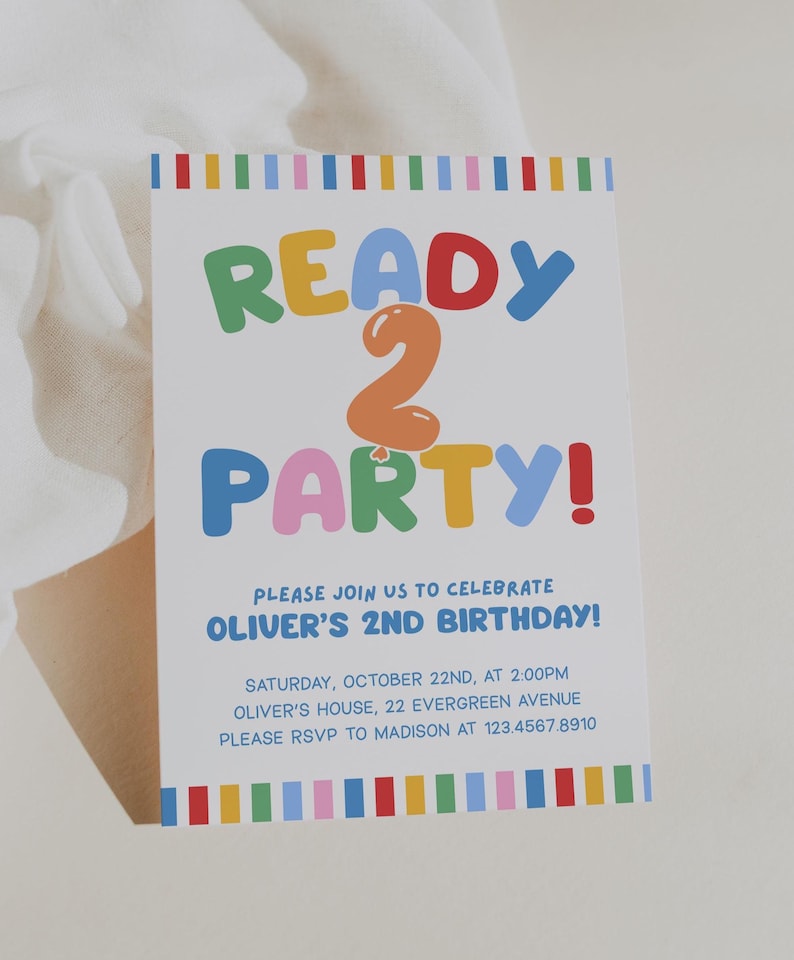 May include: A white invitation card with colorful text that reads "READY 2 PARTY!" for Oliver's 2nd birthday. The card includes the date, time, location, and RSVP information. The design features a rainbow border.