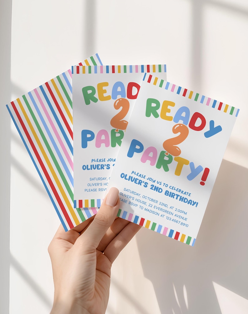 May include: Three white party invitations with colorful text and stripes. The invitations read "READ 2 READY PARTY!" and include party details for Oliver's 2nd birthday. The invitations are held by a hand.