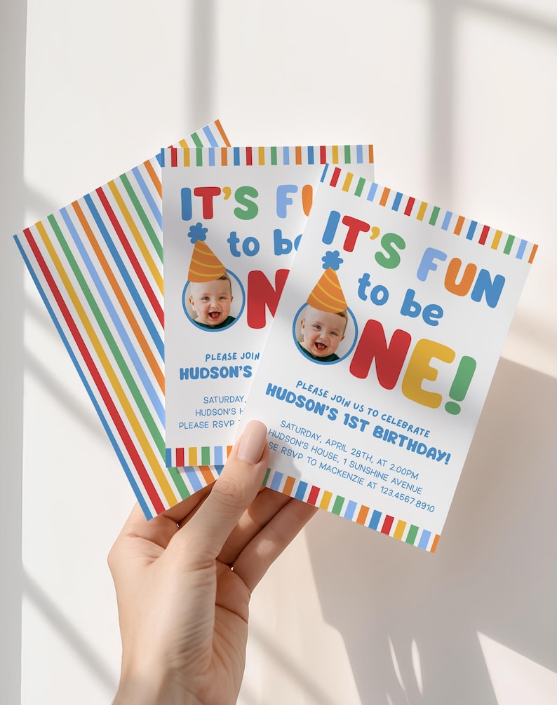 Pu&ograve; includere: Un gruppo di inviti di compleanno colorati. Gli inviti presentano il testo "IT'S FUN to be ONE!" con una foto di un bambino con un cappello da festa. Gli inviti hanno un design a righe arcobaleno.
