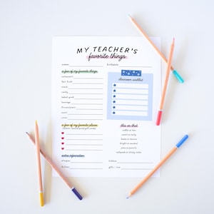 May include: A white sheet of paper with the text "MY TEACHER'S favorite things" and a fill-in-the-blank format. Several pencils with colored tips are scattered around the paper, including blue, red, green, and yellow.