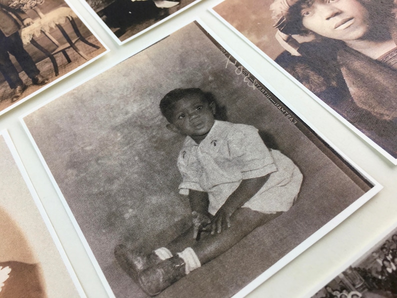 May include: A black and white photograph of a young boy sitting on the floor. He is wearing a light-colored shirt and has a serious expression on his face.
