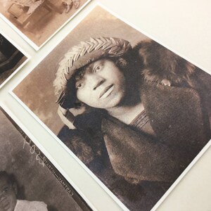 May include: A sepia-toned portrait of a person wearing a woven hat and a fur-trimmed coat. The person is looking directly at the camera.