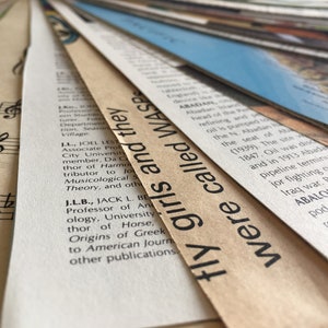 May include: Close-up of a stack of old, yellowed paper with text printed on them. The top sheet has the text "fly girls and they were called WASP" printed in black.