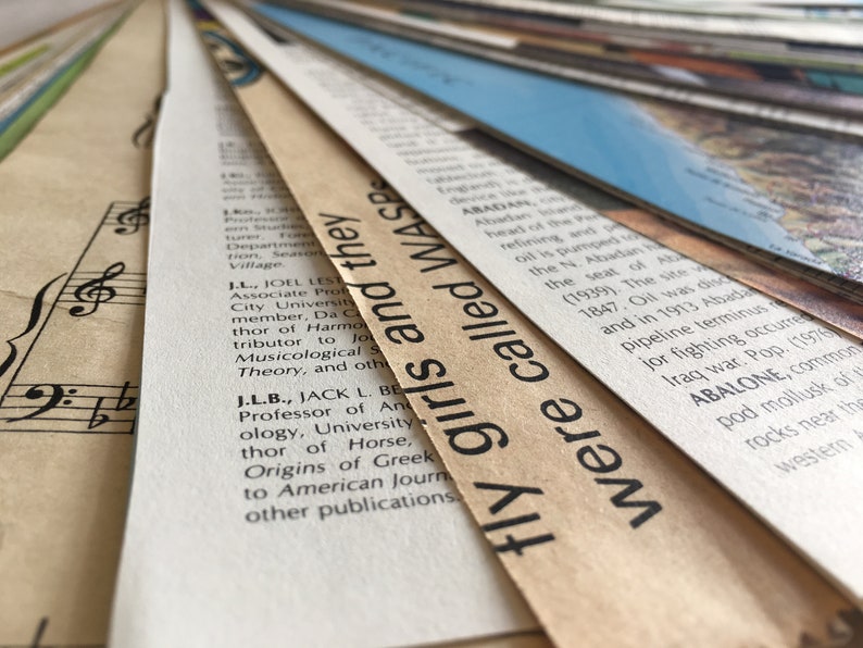 May include: Close-up of a stack of old, yellowed paper with text printed on them. The top sheet has the text "fly girls and they were called WASP" printed in black.