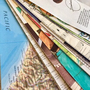 May include: A close-up of a stack of papers with a map of Arequipa, Peru, on top. The map is in shades of brown, green, and blue. The papers below are a mix of colors and textures, including music sheets, a map of the Pacific Ocean, and a page of text.