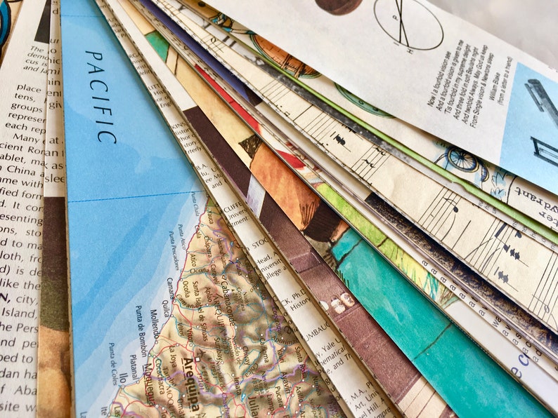 May include: A close-up of a stack of papers with a map of Arequipa, Peru, on top. The map is in shades of brown, green, and blue. The papers below are a mix of colors and textures, including music sheets, a map of the Pacific Ocean, and a page of text.