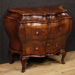 Könnte beinhalten: Vintage Holzkommode mit geschwungener Bombe-Form. Die Kommode hat drei Schubladen mit Messingbeschlägen und steht auf vier geschwungenen Beinen. Das Holz hat einen satten, warmen Braunton mit gemasertem Muster.