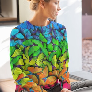 May include: A colourful sweatshirt with a rainbow pattern of butterflies. The butterflies are in shades of blue, green, yellow, orange and pink.