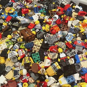 May include: A large collection of assorted plastic building block minifigures and various accessories in a wide array of colors including red, blue, yellow, green, and brown. The pile contains numerous torsos, heads, legs, and small plastic parts.