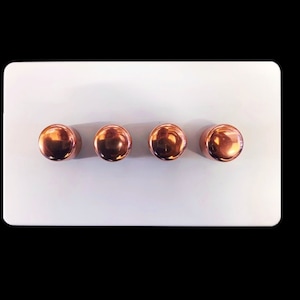 May include: A white light switch plate with four round copper-coloured toggle switches.