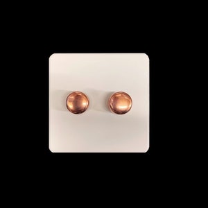 May include: A pair of small, round, copper-coloured earrings.